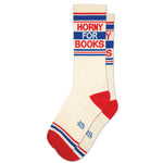 A pair of white gym crew socks with red and blue text that reads 'HORNY FOR BOOKS'.
