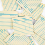 Stack of yellow lined notepads with blue lines on a white background
