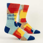 Blue Q Crew socks. Geometric, abstract color blocks of red, orange, yellow and dark blue sit on a light blue background. In dark blue text on the top portion are the words "Cool-Ass Grandpa"