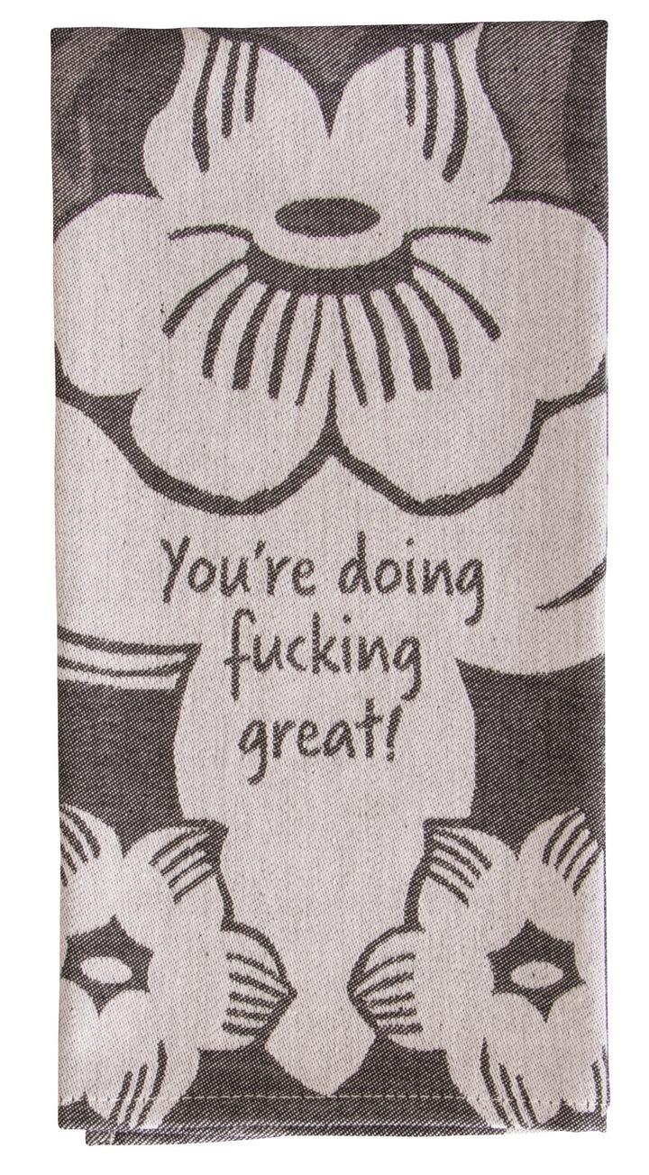 A black and grey woven Blue Q dish towel with large flowers. At the bottom of the largest flower it reads, "You're doing fucking great!"