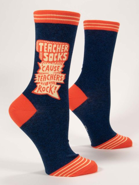 Blue Q funny crew socks. Navy blue with orange accents on the toe, heel and top of sock. In a graphic orange and cream typography the top upper portion read "Teacher socks 'cause teachers rock"
