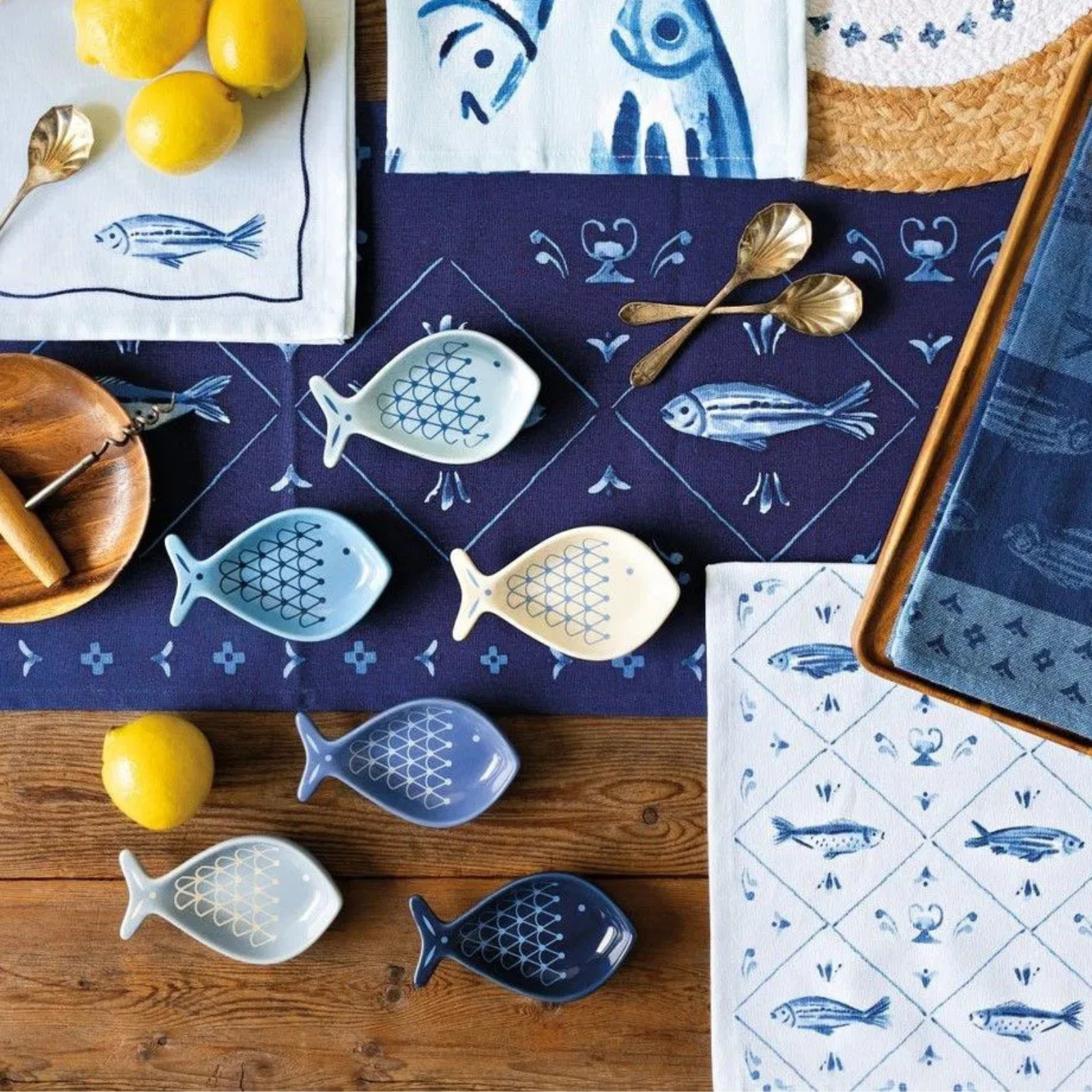 Table setting with blue and white fish-patterned tablecloth, plates, and decorative items on a wooden surface.