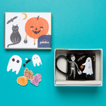 Halloween-themed mug with skeleton, ghost, and pumpkin design in an open box on a blue background.