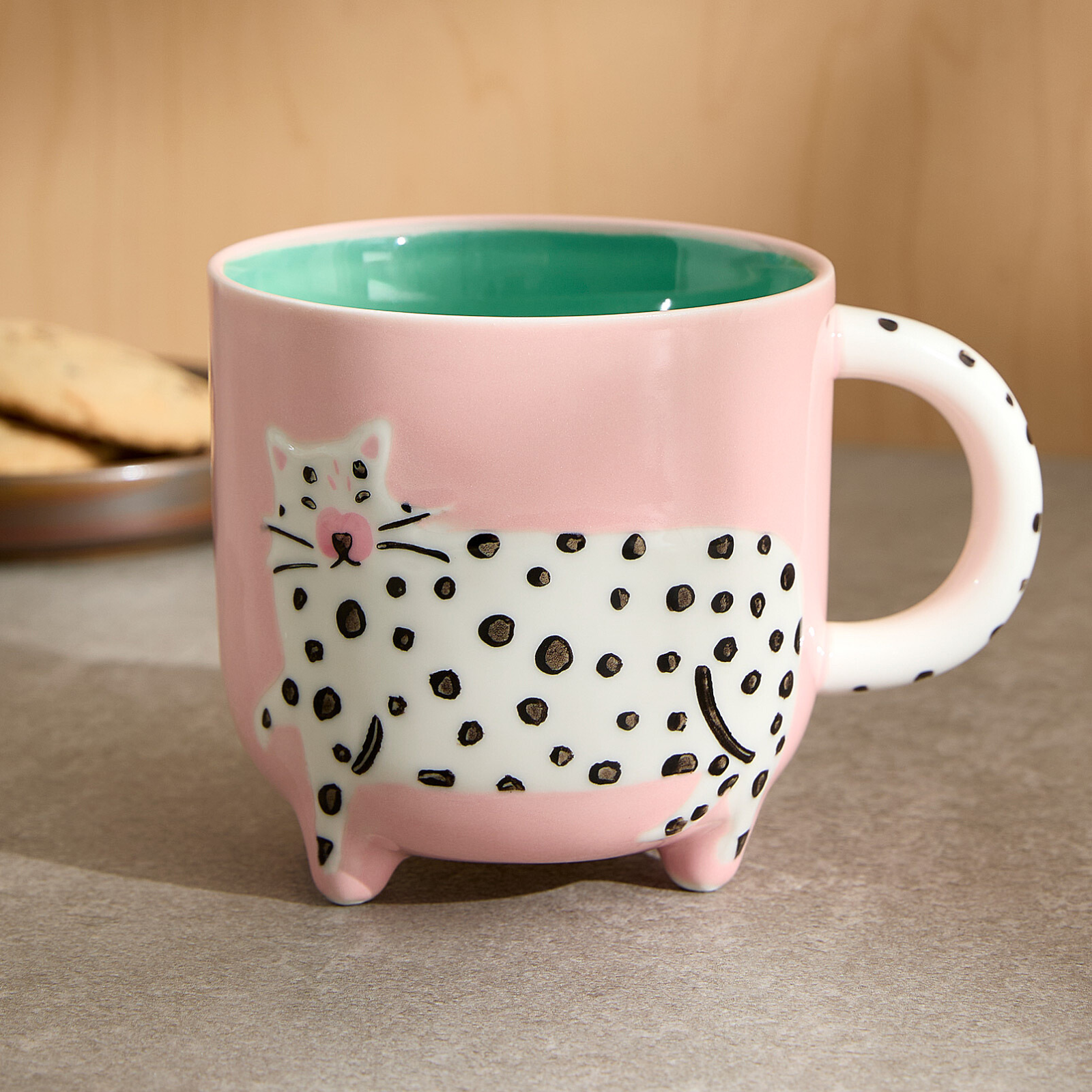 Pink mug with a cat design on a beige surface