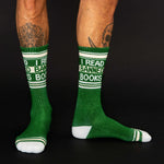 Green socks with 'I Read Banned Books' text worn by a person on a black background