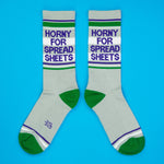 Gray socks with text that reads "Horny for Spread Sheets" and green accents on a blue background
