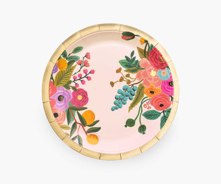 Rifle Paper Co. Paper plate. A pale pink background with a muli-colored floral illustrated pattern on both sides on the right and left side of the plate. Gold border around the edge of the plate. 