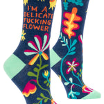 Blue Q crew socks. Navy blue with a green, yellow, blue and pink floral pattern. In orange text it reads "I'm a delicate fucking flower"