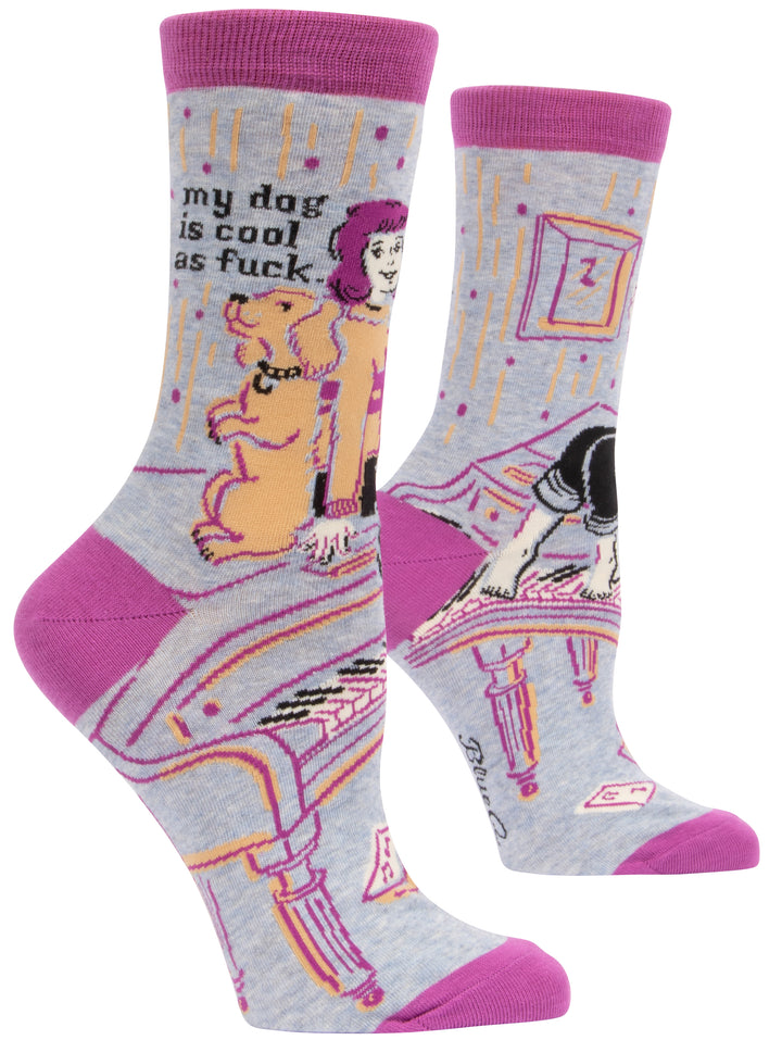 Blue Q crew socks. Grey with purple accent on the ankle, heel and toe. An illustration of a woman with a dog sitting on top of a piano. Above them reads "My dog is cool as fuck" 