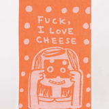 Blue Q dish towel. Orange with white polka dots, at the bottom a girl is holding a piece of cheese up to her face and looking through the holes. Above her heads reads "Fuck, I love cheese"