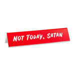 A red desk sign with white text saying 'NOT TODAY, SATAN'. 