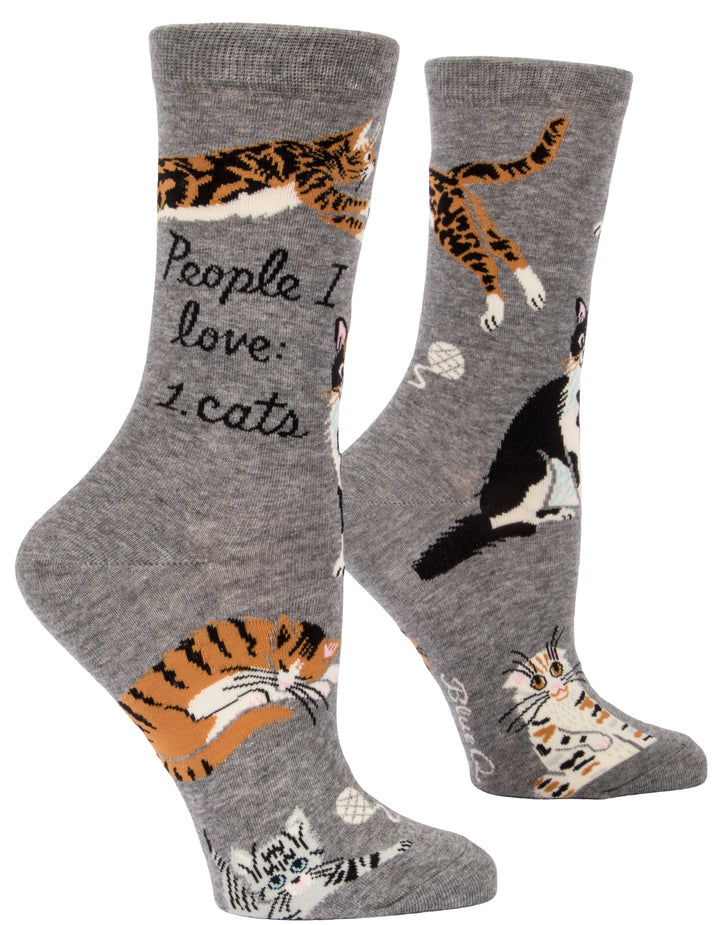 Blue Q crew socks. Grey with multiple orange, black and white cats illustrated on the sock. In the middle in black script reads "People I love: Cats."